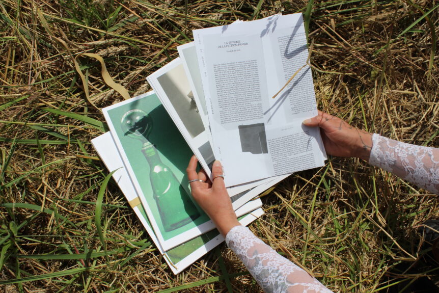 dans l'herbe, des mains tiennent des feuilles sur lesquelles sont imprimées le texte d'un livre